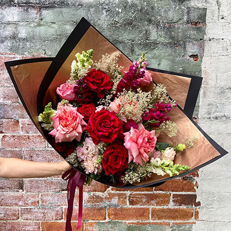 Bouquet of deep red and pink roses with seasonal flowers of snapdragons and stock
