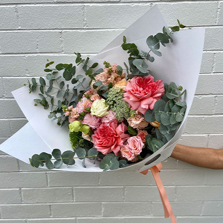Pastel flower bouquet of seasonal flowers including roses, stock, spray roses, queen annes lace and lissianthus